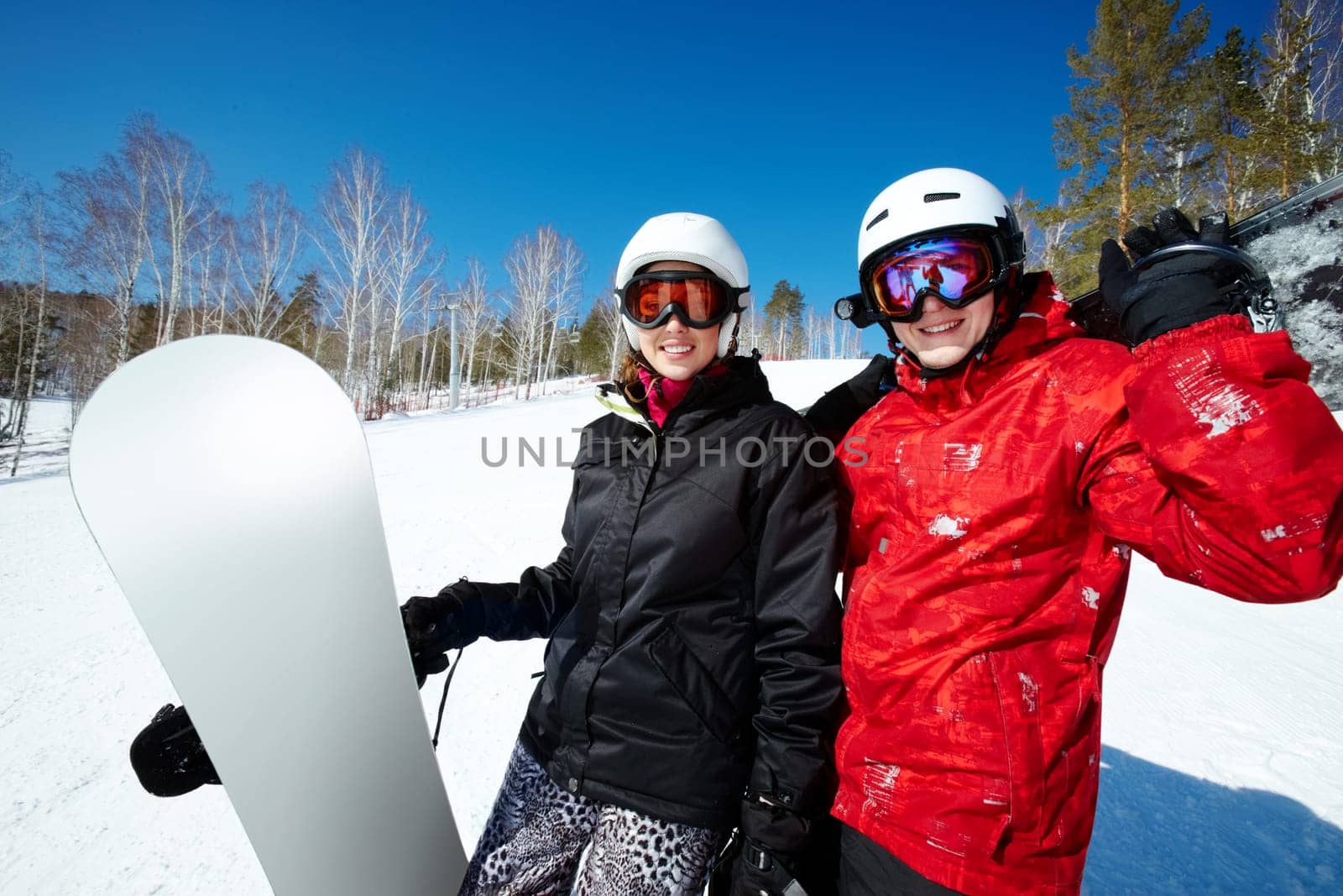 Portrait of happy couple of snowboarders outside during winter vacations