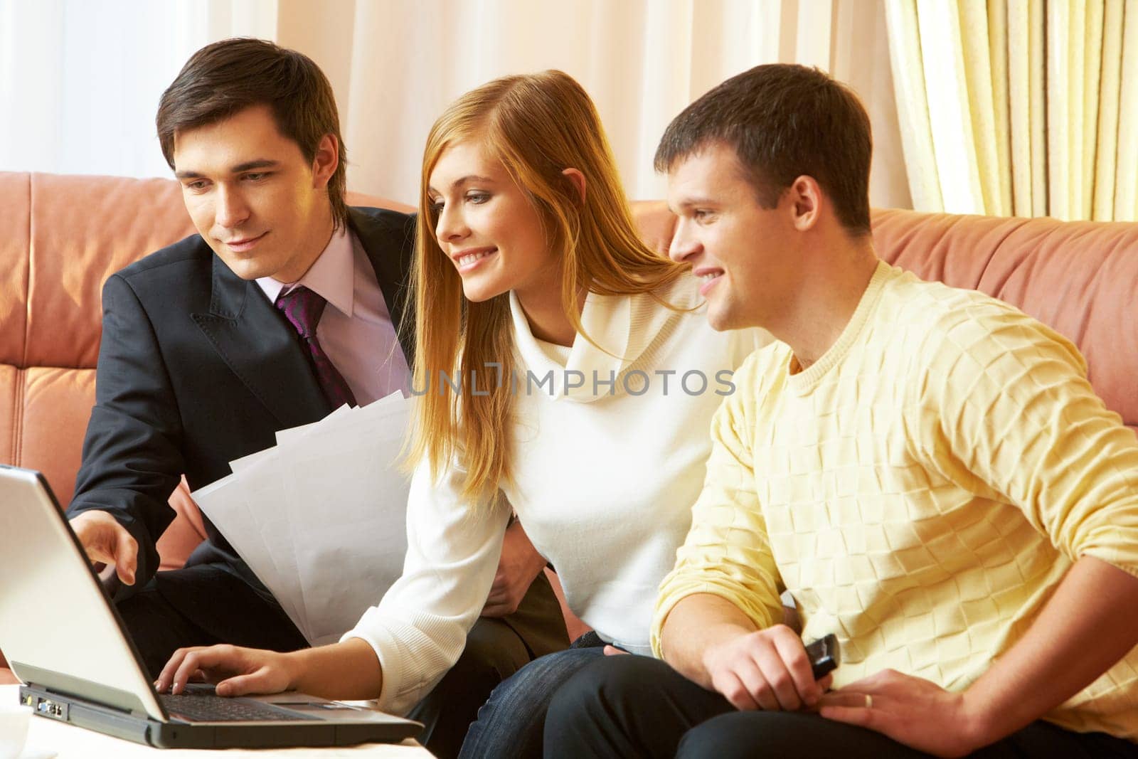 Portrait of a businessman and young couple looking at something in laptop