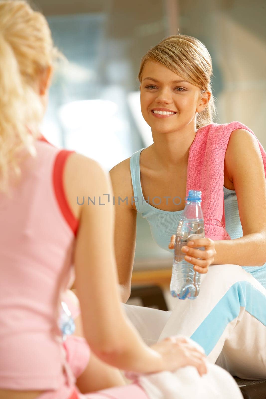 Photo of two teenage girls sitting in the sports gym and communicating
