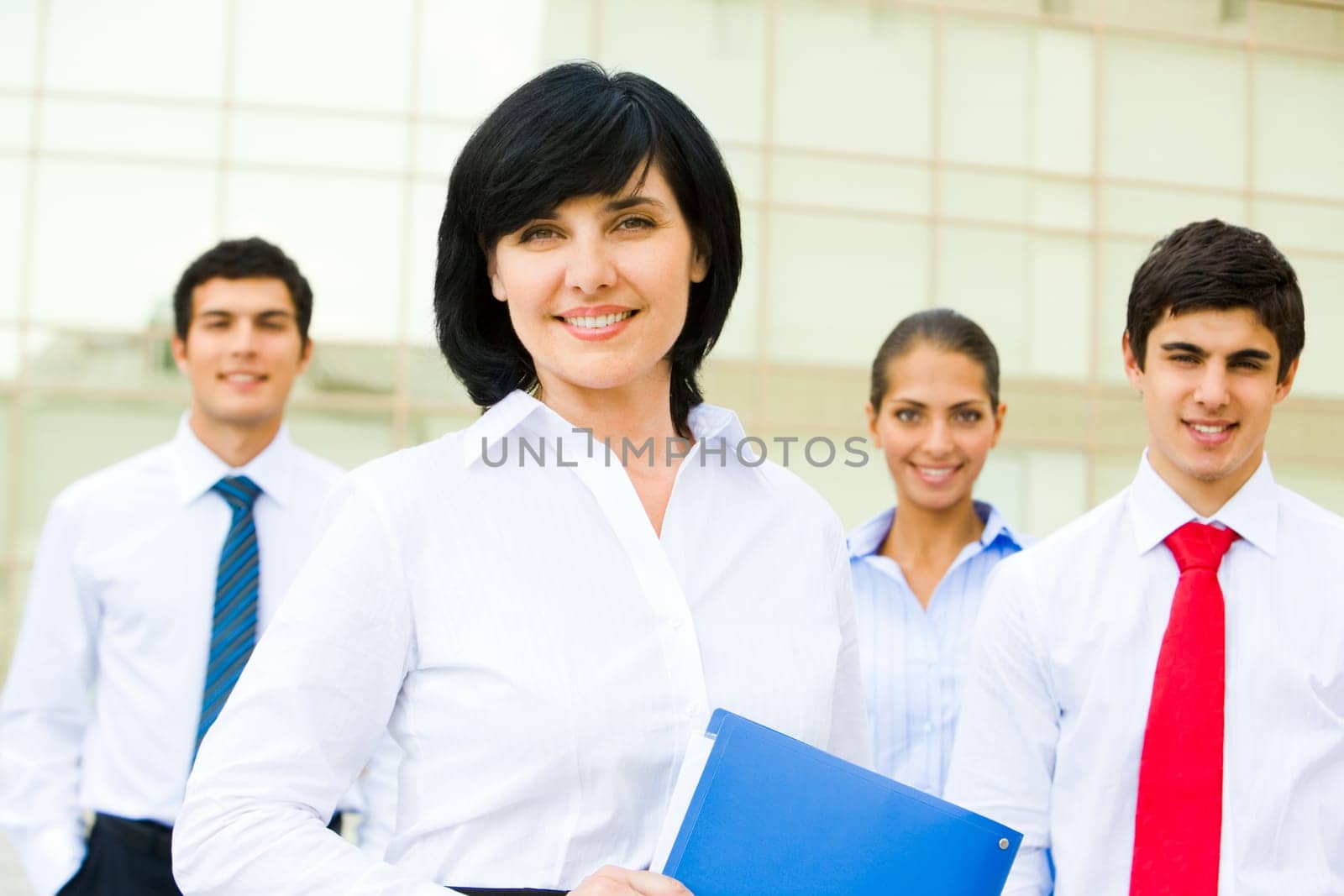 Portrait of attractive leader of friendly business group standing at background