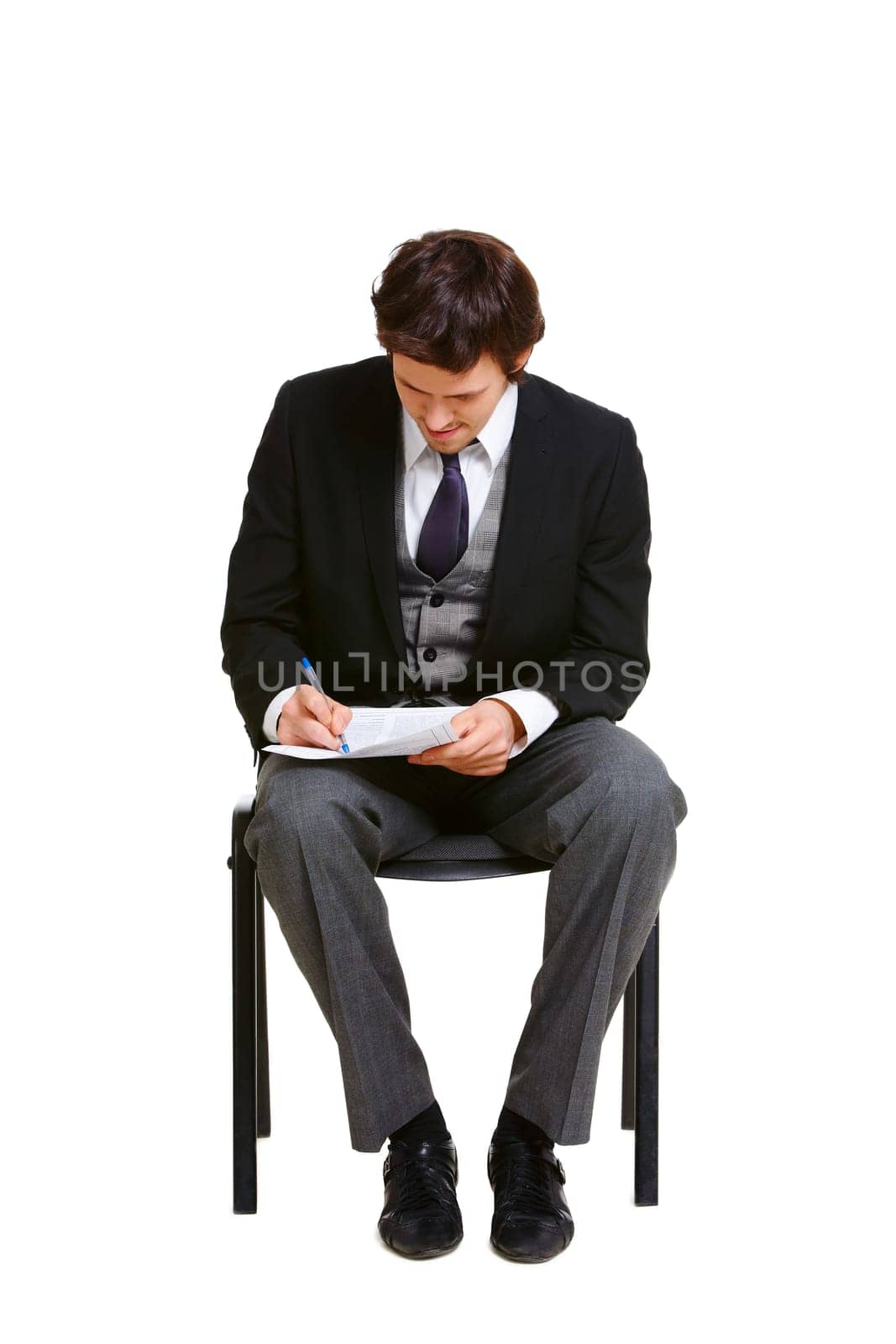 Confident businessman making notes while sitting on chair