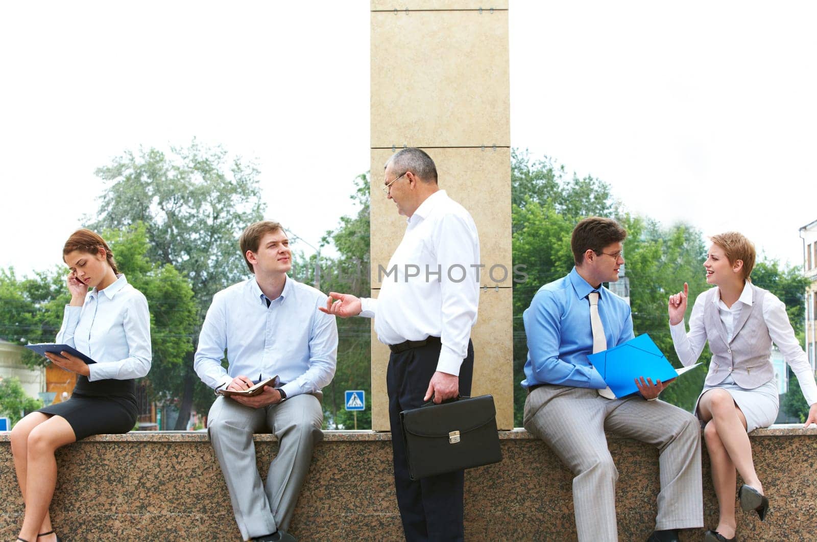 Image of several business partners interacting and working outside with papers