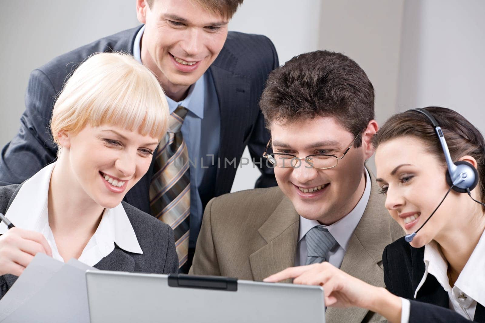 Team of four business people seriously gazing at a screen of laptop