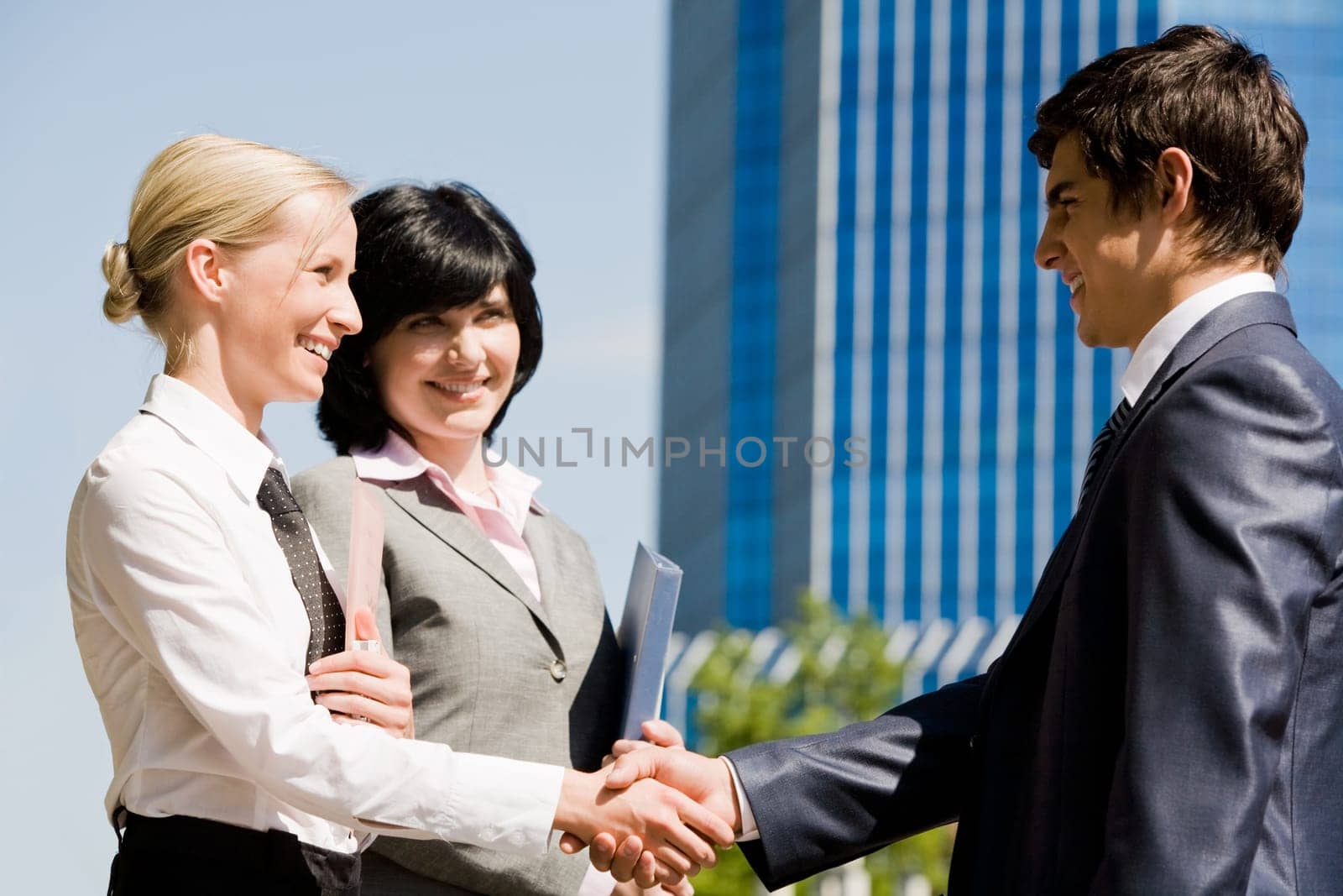 Photo of successful associates handshaking after striking deal outdoors at meeting
