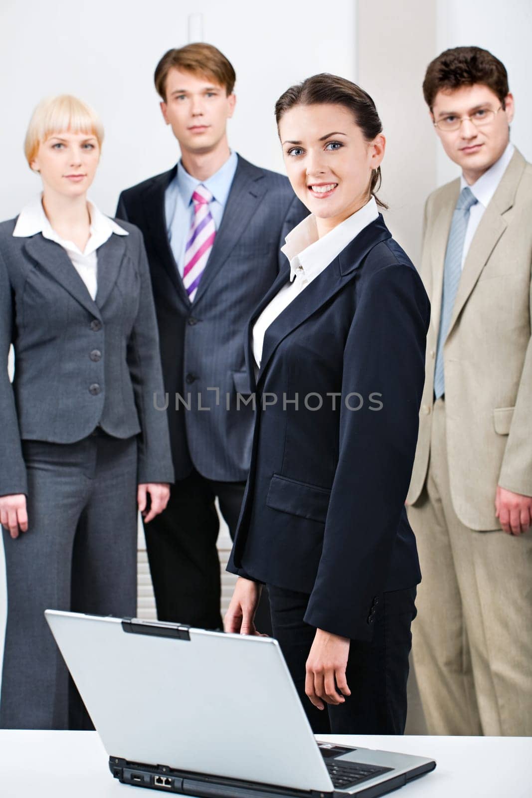 Confident woman in suit standing in front of business people