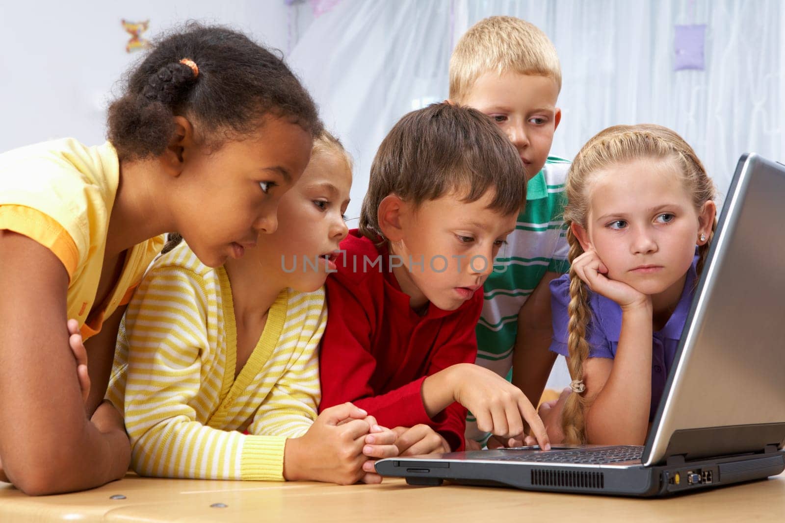 Portrait of smart schoolgirls and schoolboys looking at the laptop