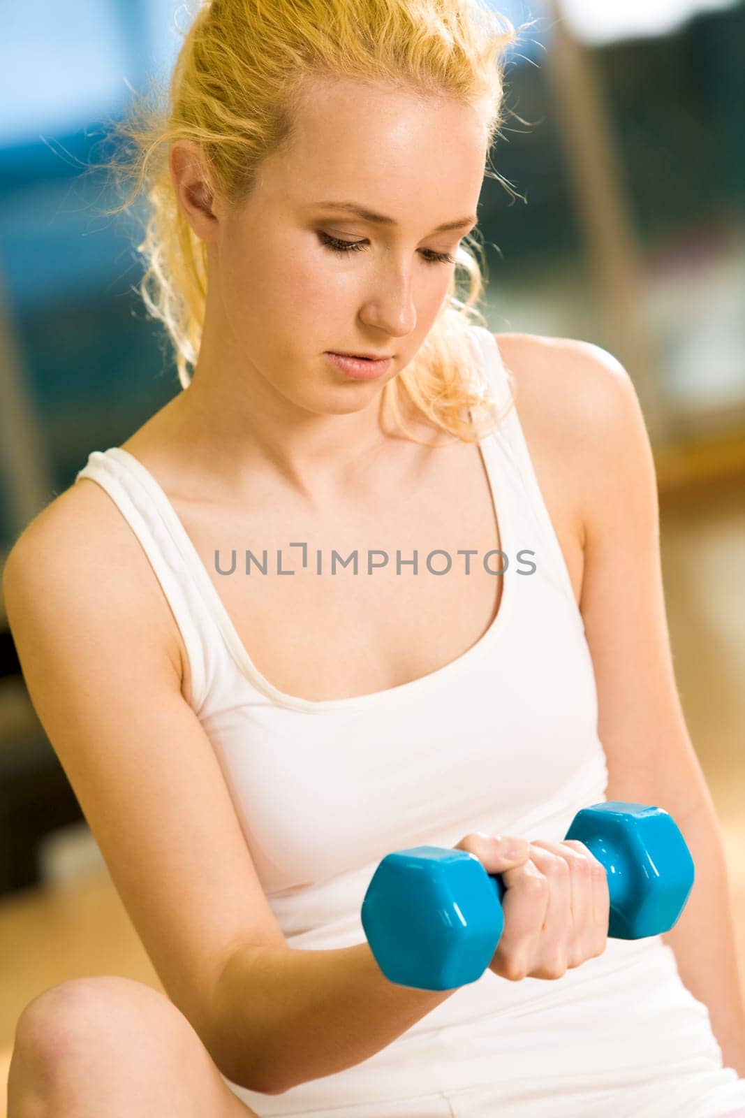 Portrait of strong female doing exercise with dumbbells in sports gym