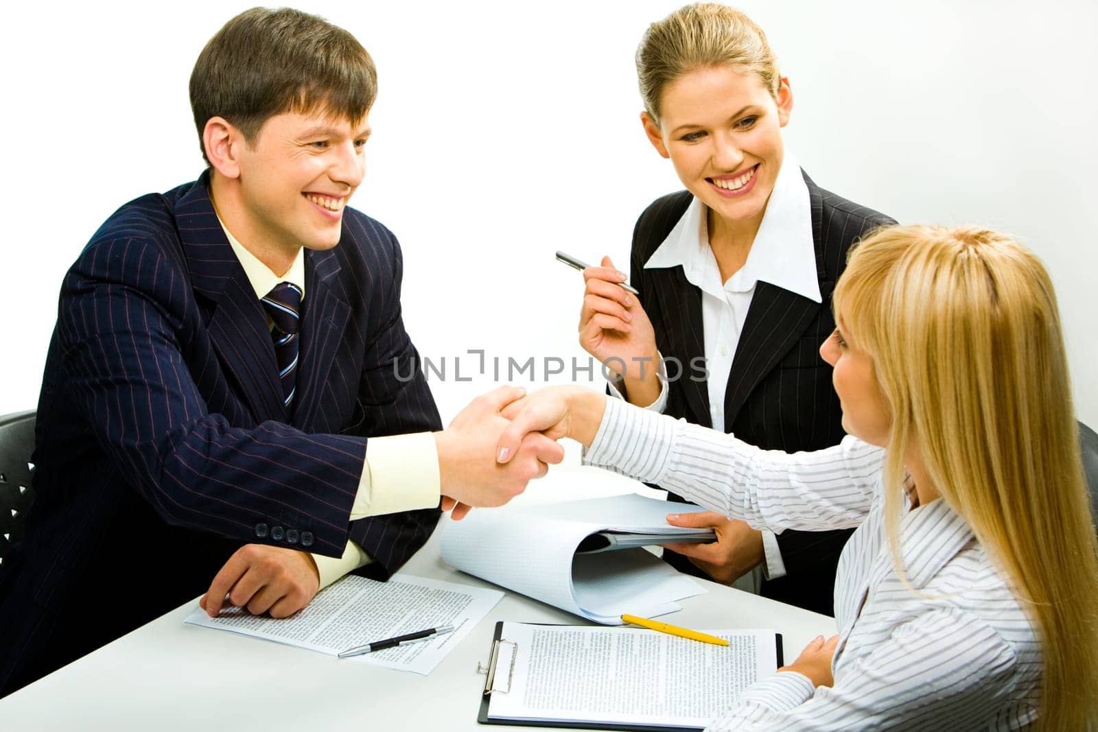 Portrait of two happy business partners shaking hands during business meeting with attractive smiling secretary sitting near by