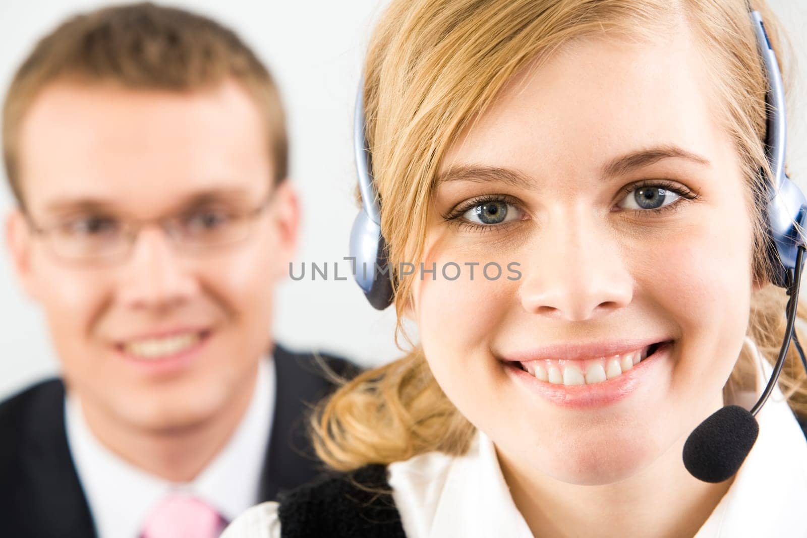 Face of pretty secretary wearing headset on background of confident businessman