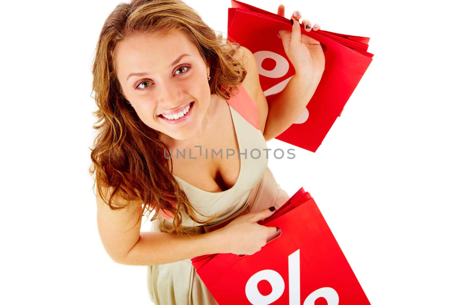 Above view of a girl holding paper bags with discount symbol, looking at camera and smiling