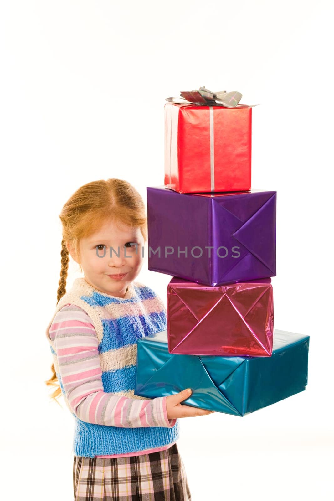 Portrait of little girl with pile of Christmas gifts in hands looking at camera