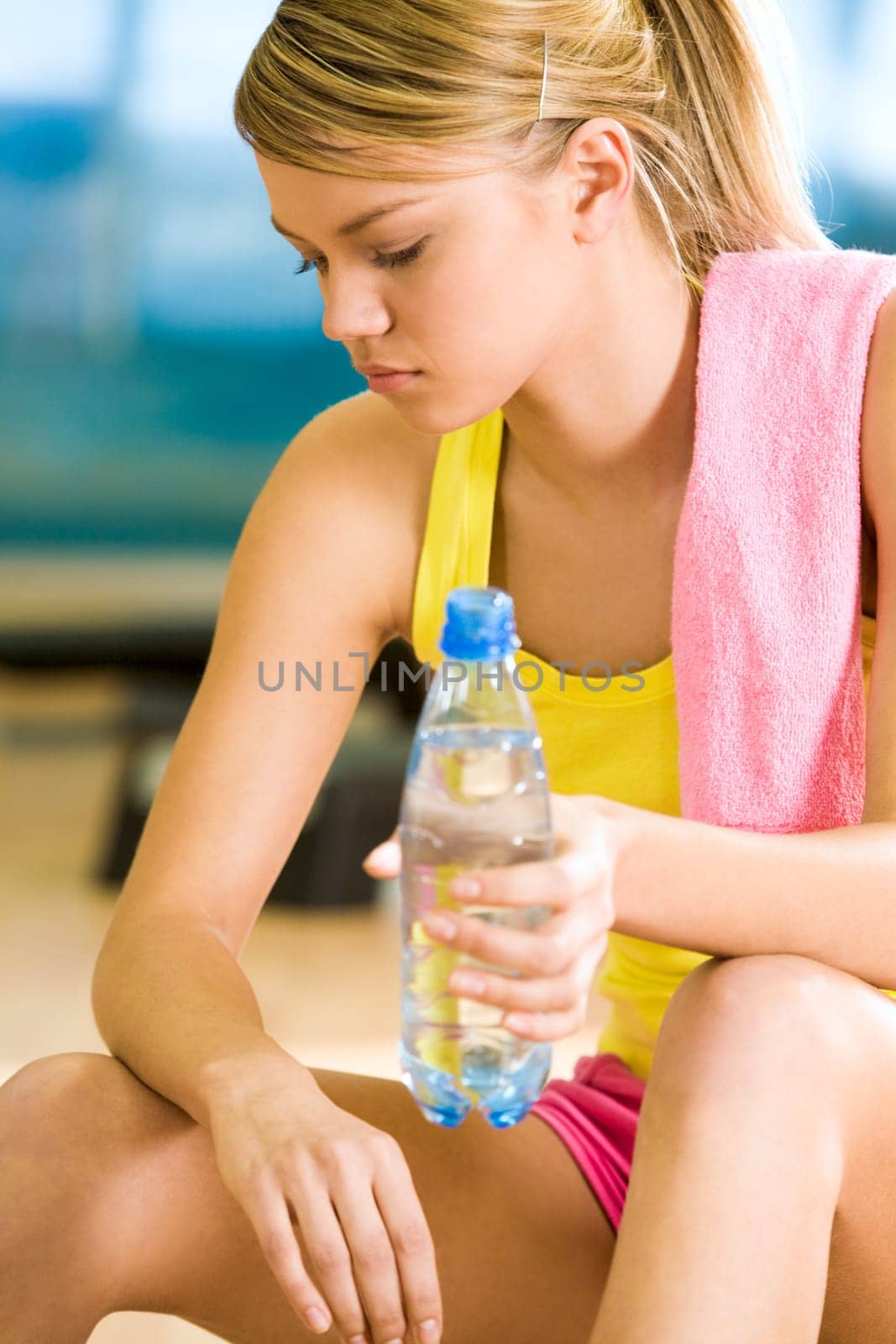 Photo of exerted female having a drink of water after difficult exercises