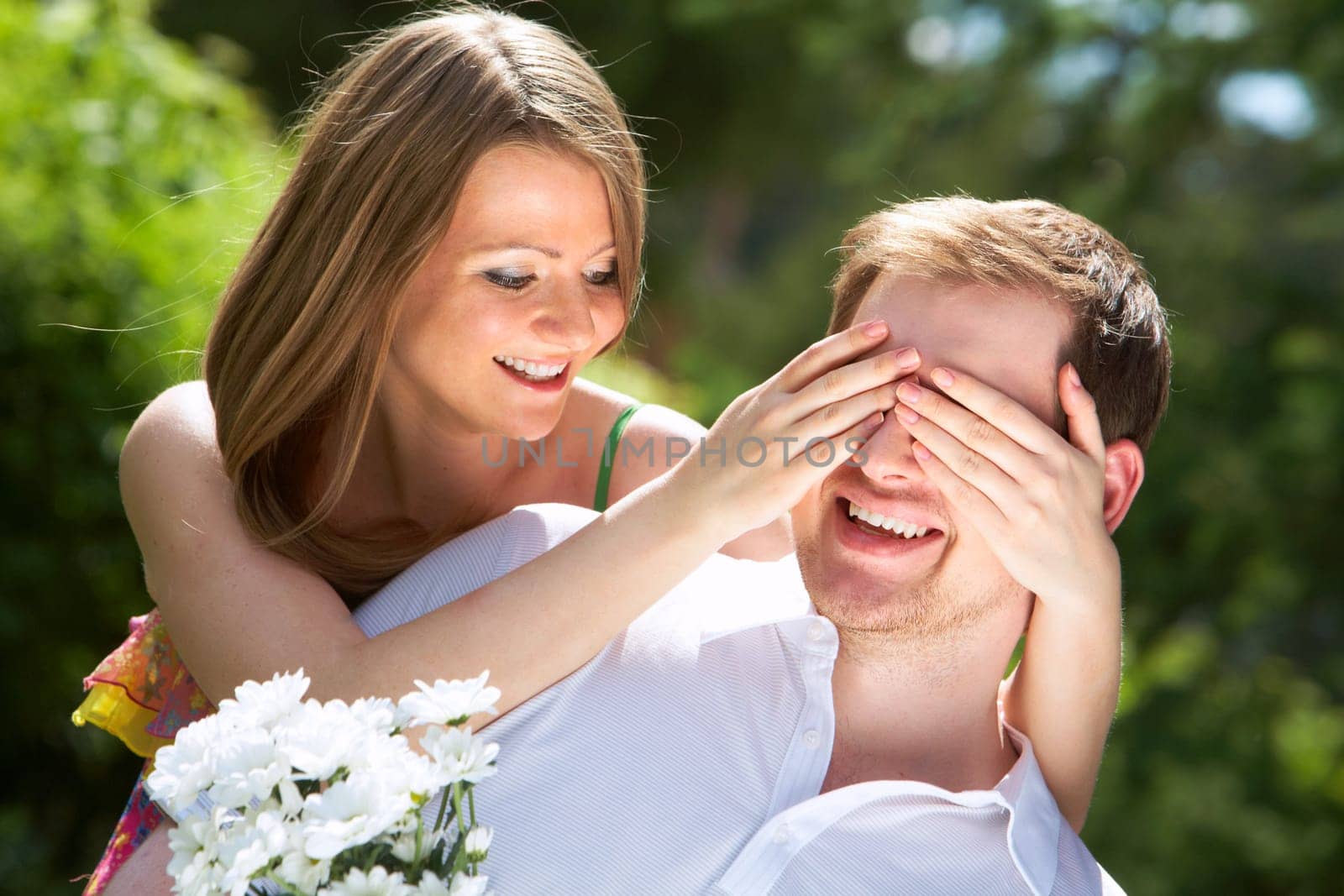 Photo of happy girl closing her boyfriend eyes by hands