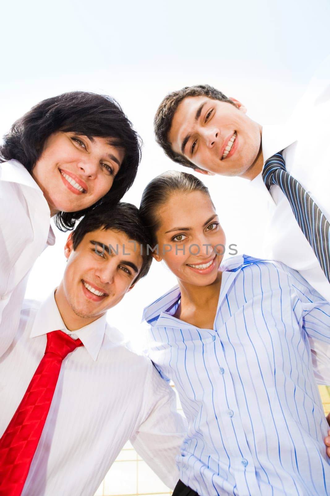 Photo of several successful partners embracing each other and looking at camera with smiles