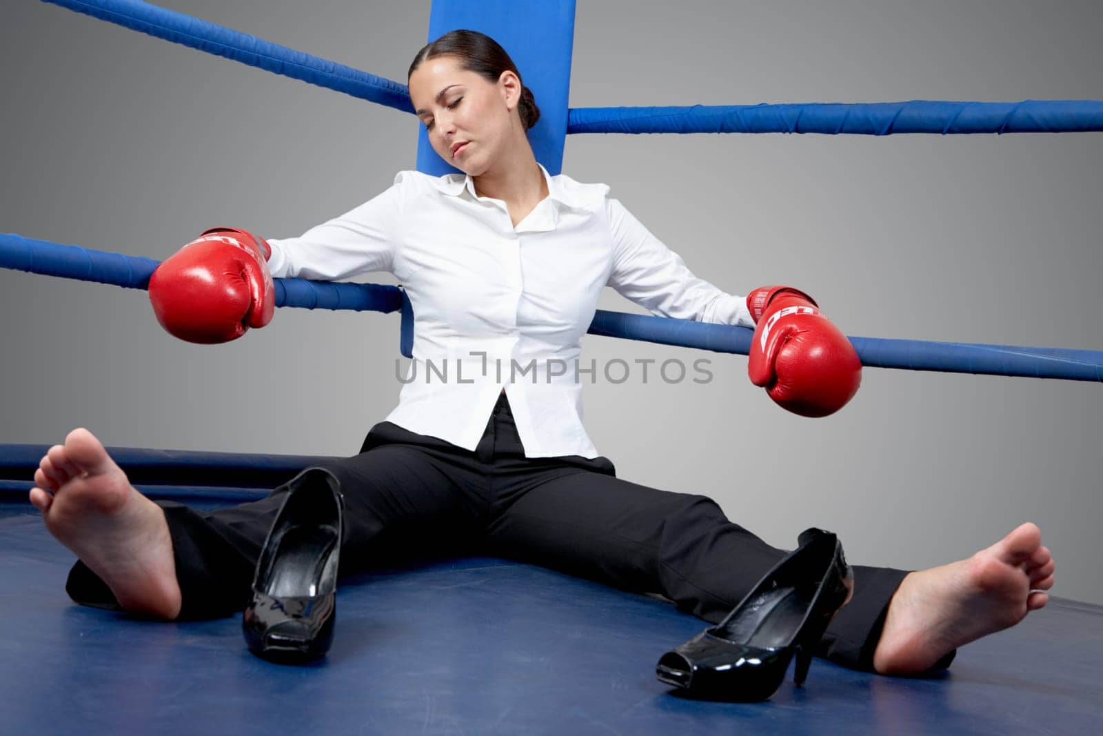 Portrait of tired businesswoman in boxing gloves sleeping on boxing ring