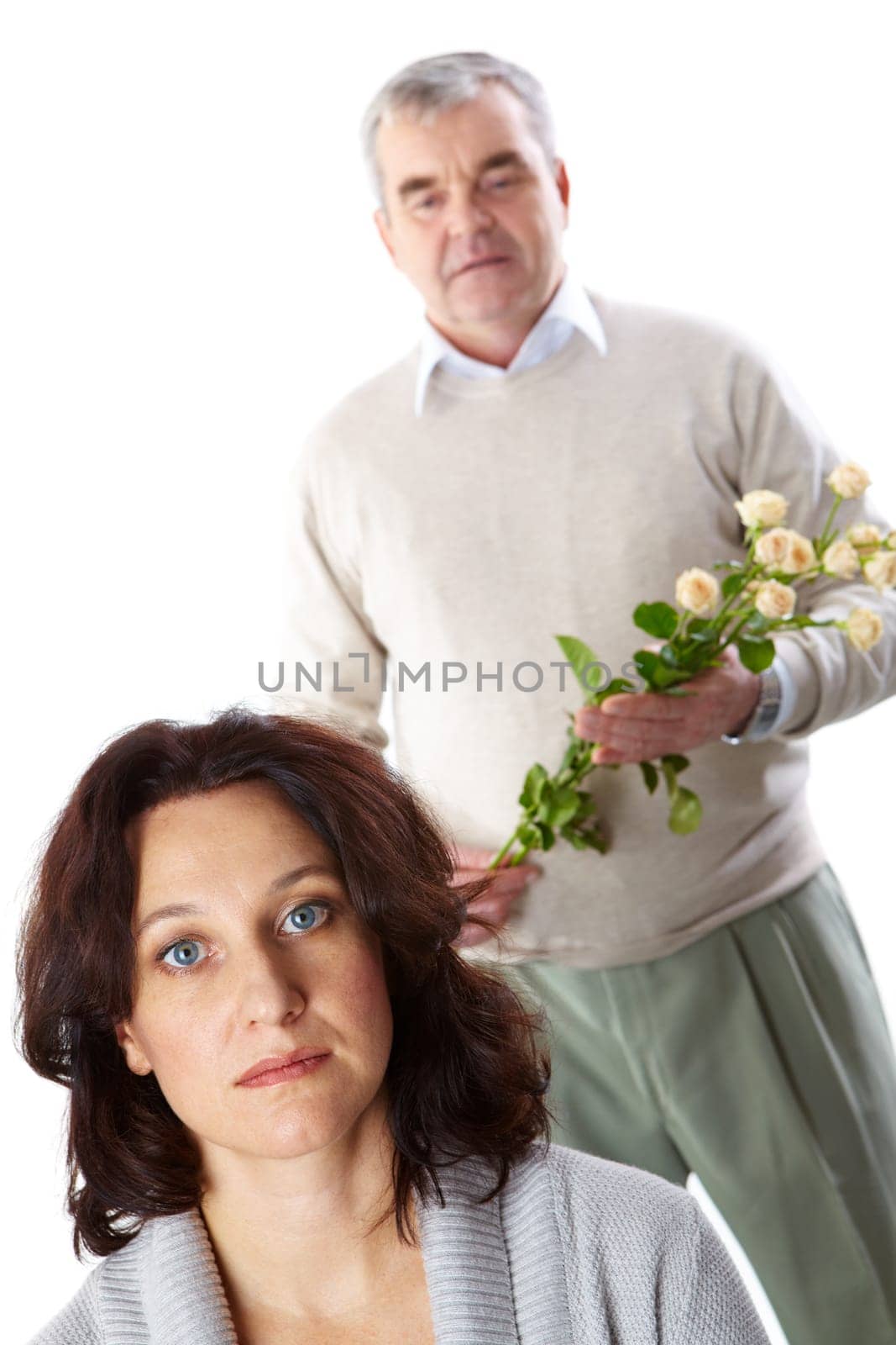Portrait of mid aged brunette looking at camera with man holding flowers behind her