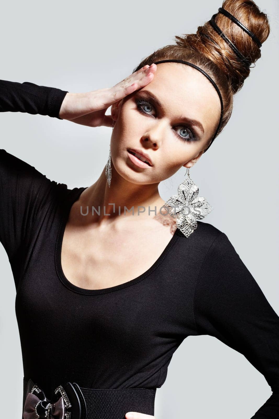 Gorgeous woman with fantasy earrings posing on grey background