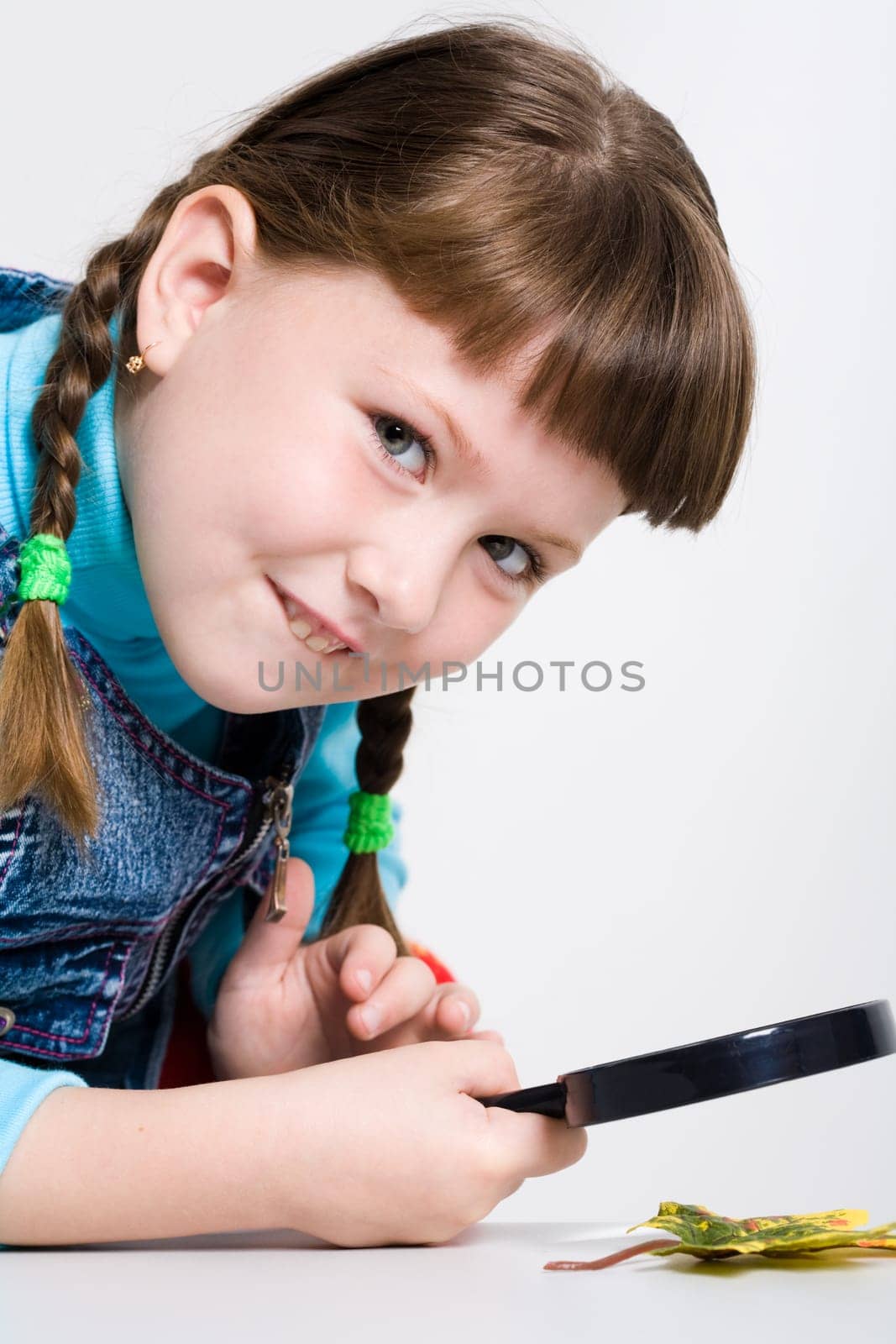 Image of schoolgirl with magnifier in hand looking at camera with smile