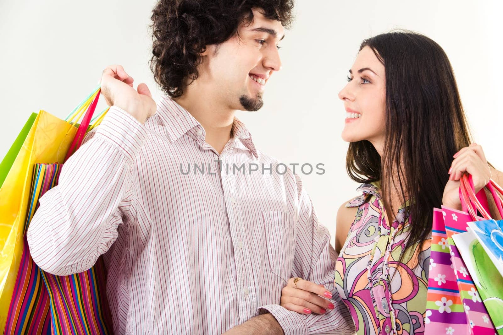 Portrait of happy couple with shopping bags looking at each other on white background