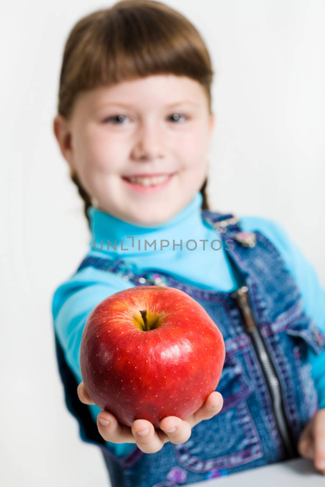 Close-up of fresh red apple in schoolgirls hand with her at background