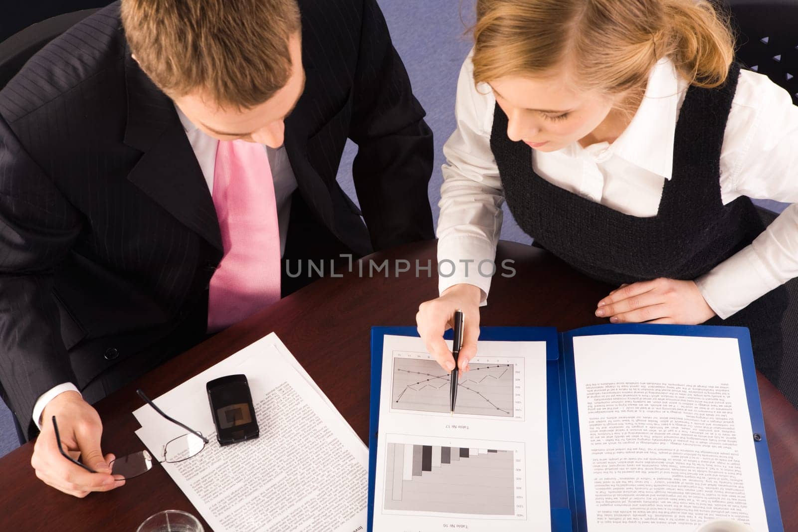 View from above of business partners sitting at table and working with documents