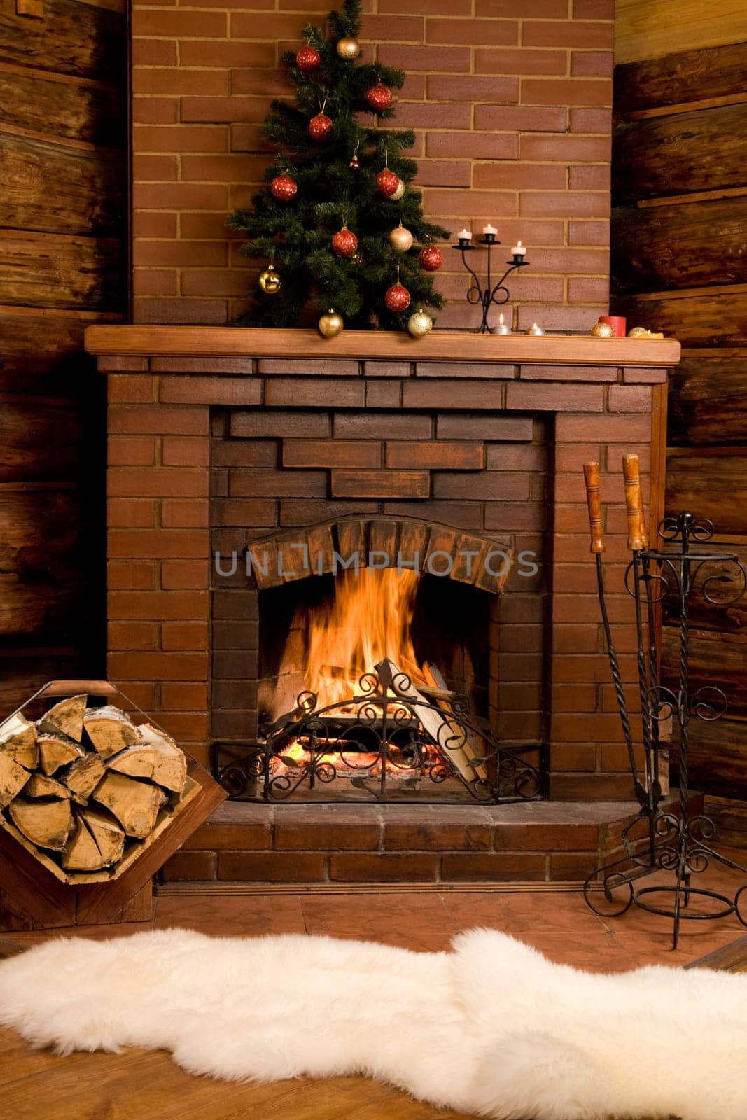 Photo of fireplace with firewood and warm white fur near by