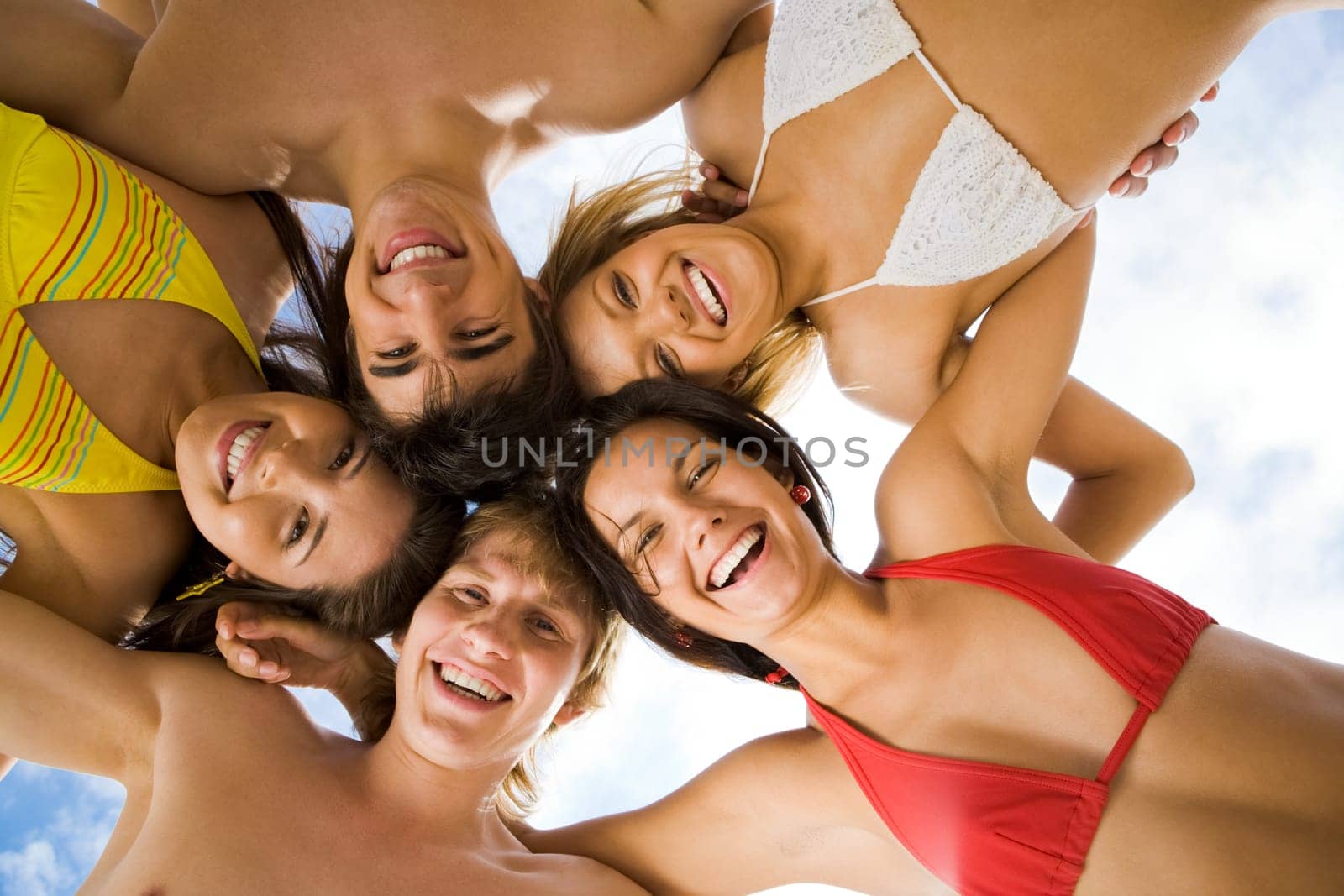 Below view of joyful teens looking at camera with smiles