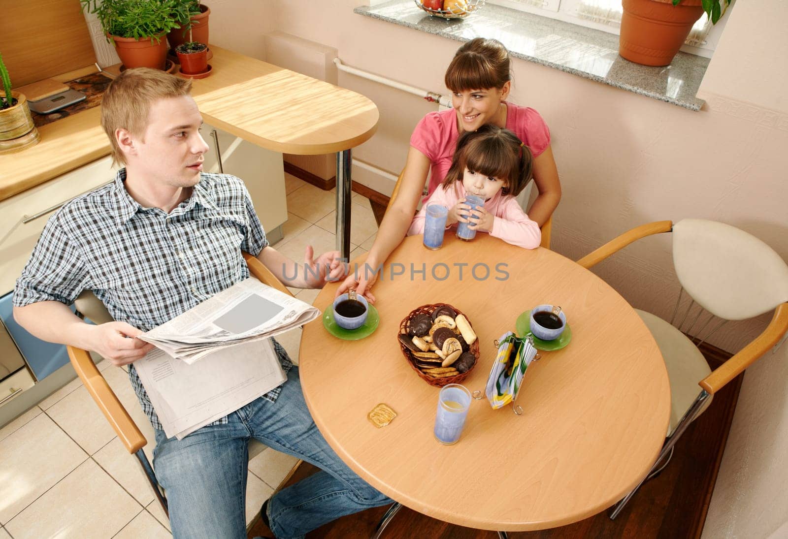 Happy couple looking at each other during breakfast with their daughter near by