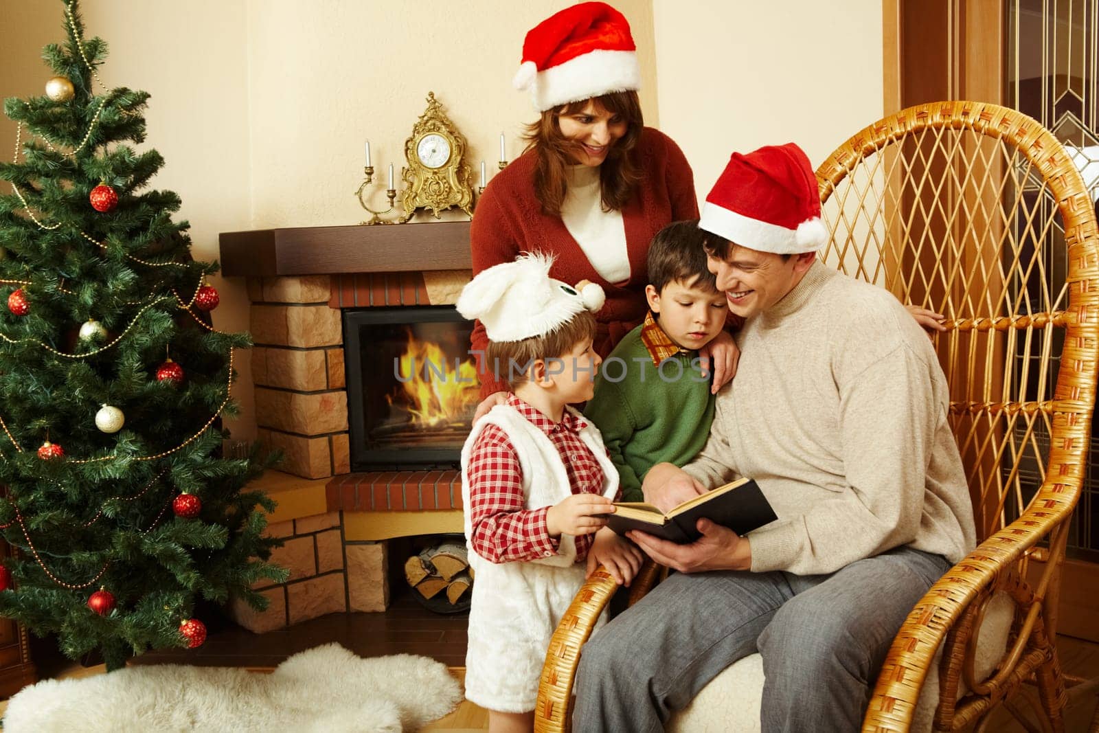 Portrait of family gathered together to read interesting fairy tale with decorated fir tree behind