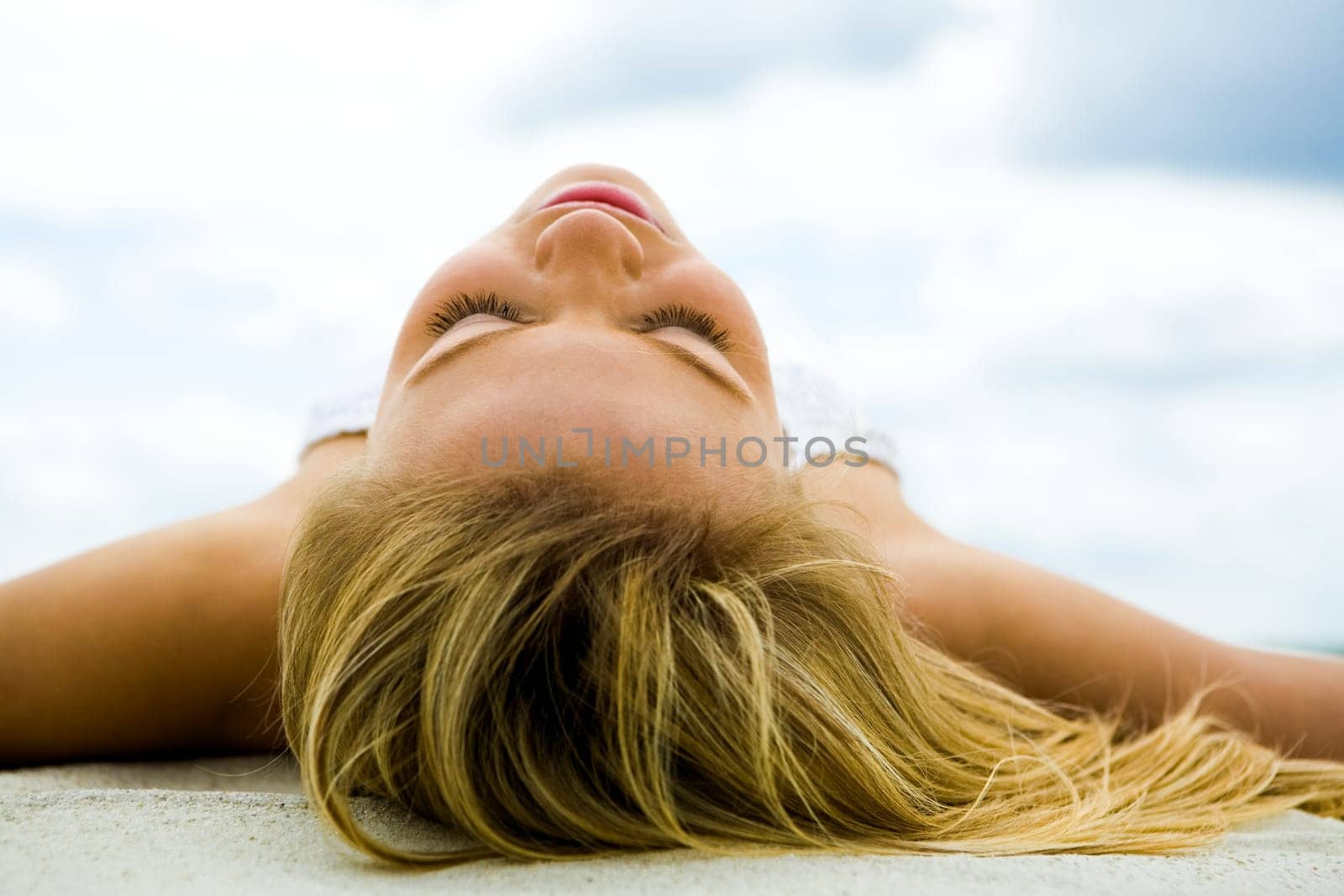 Image of serene female sunbathing on sand