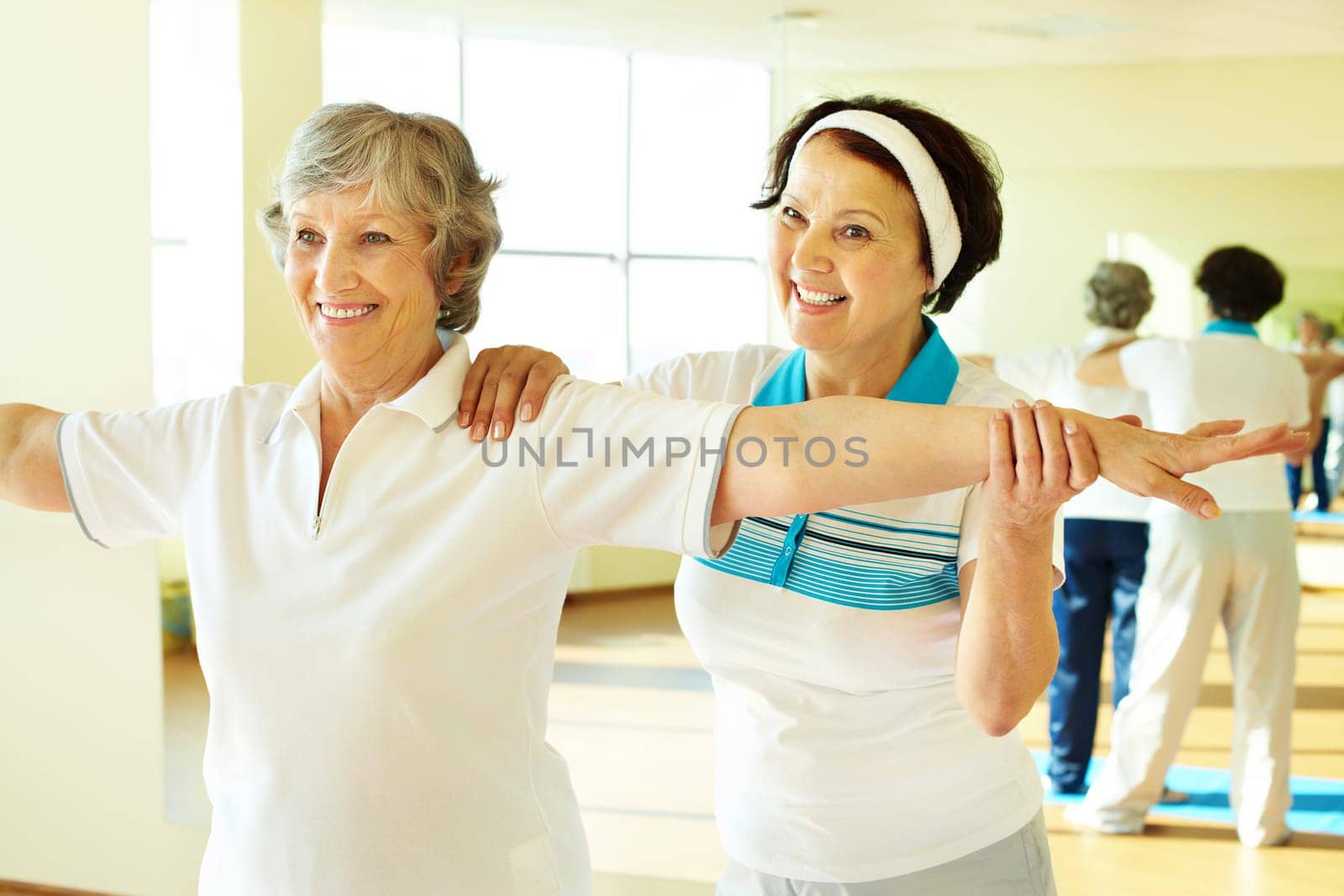 Portrait of sporty female supporting her friend while doing physical exercise in sport gym