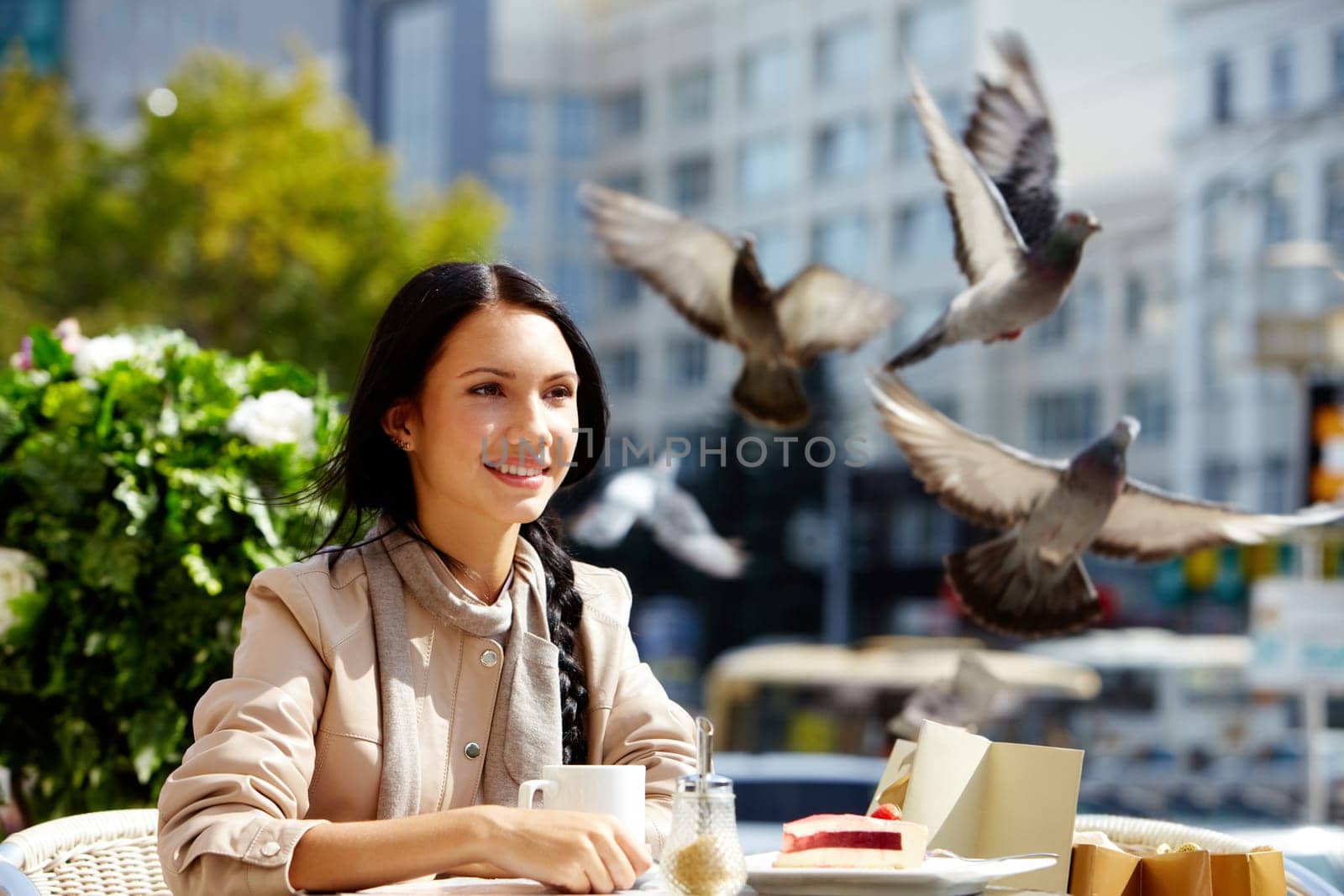 Image of happy female in open air cafe having coffee with cake in urban environment
