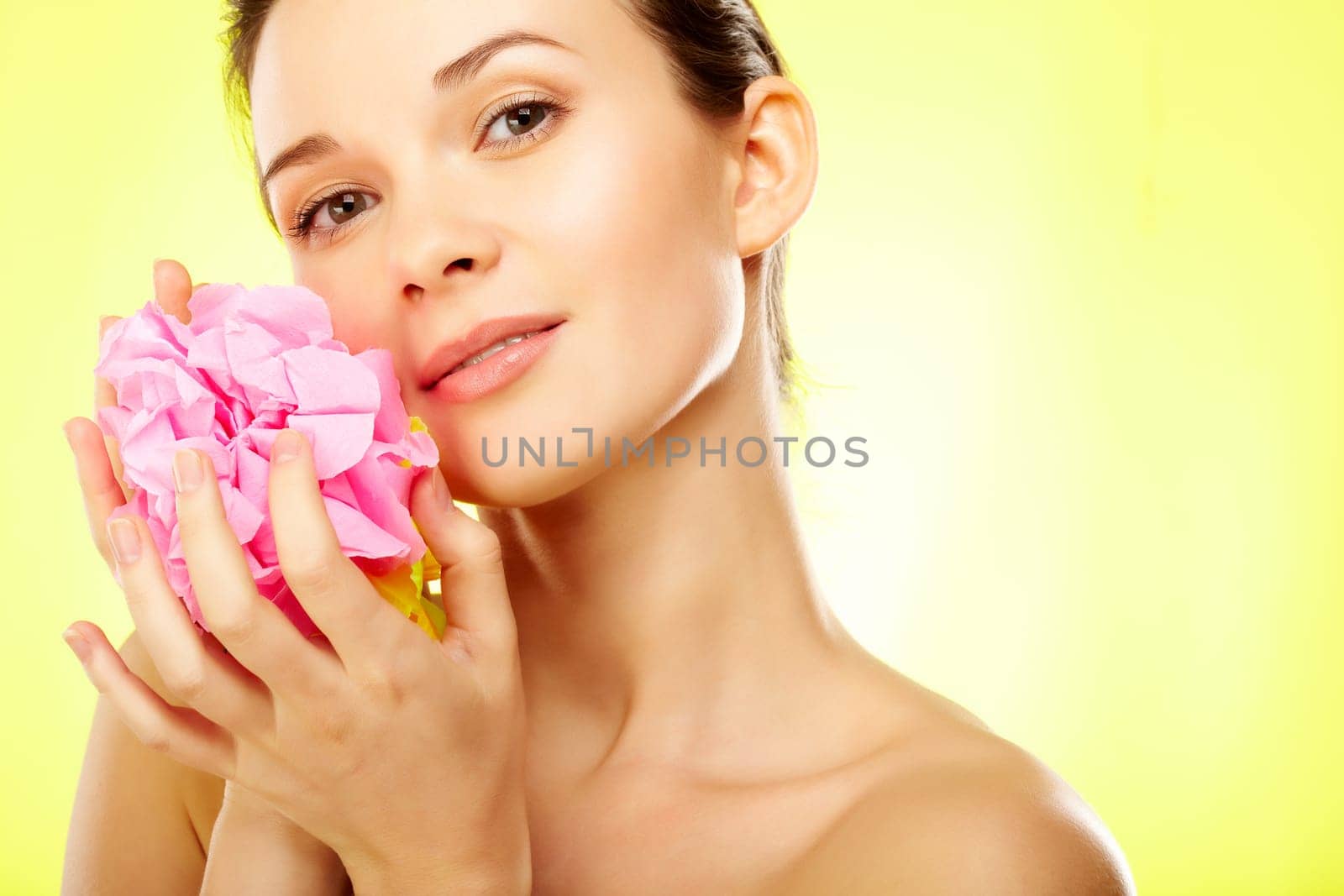 Gorgeous woman with pink flower over yellow background