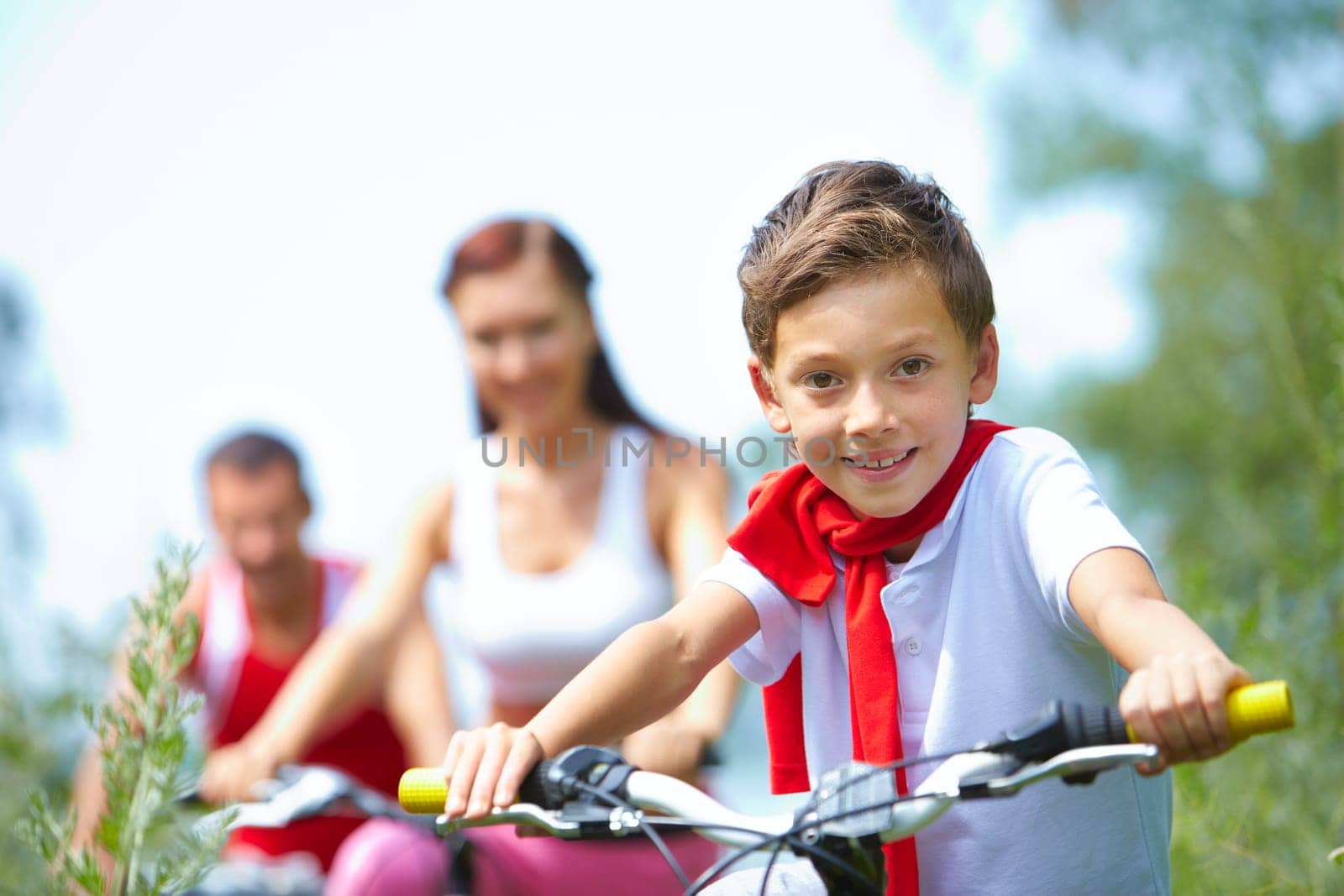 Portrait of a happy boy looking at camera and smiling with his parents in the background
