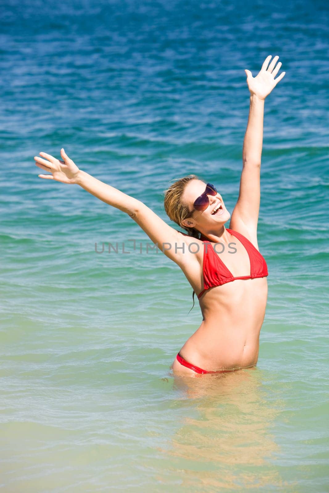 Photo of joyful woman standing in water and enjoying summer vacation