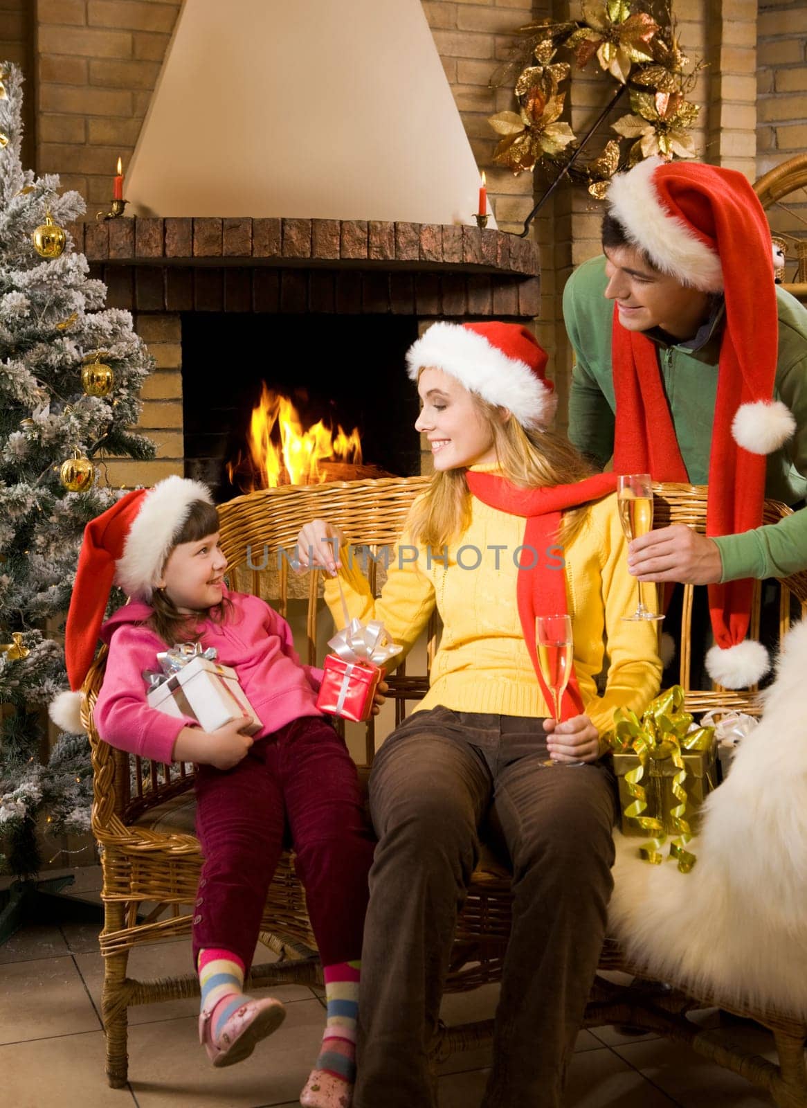 Portrait of happy parents and their cute daughter with presents at home on Chrismas day