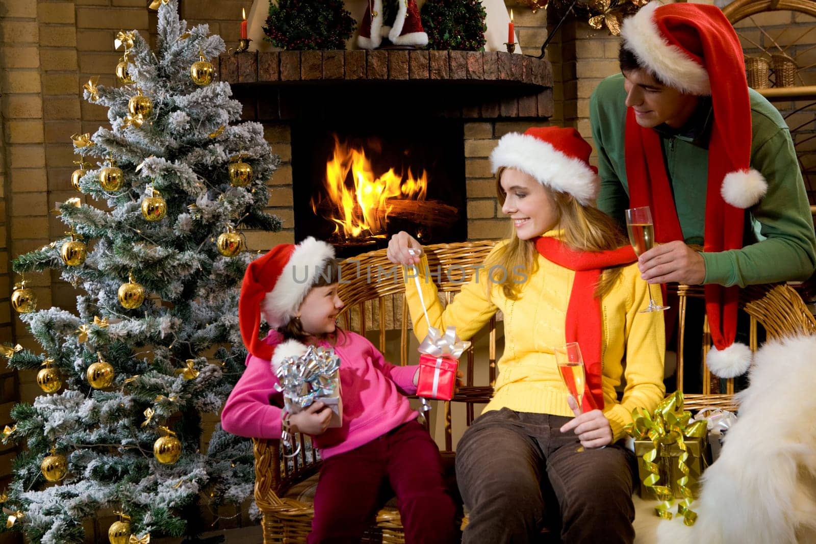 Laughing daughter looking at her parents while they giving her Christmas presents
