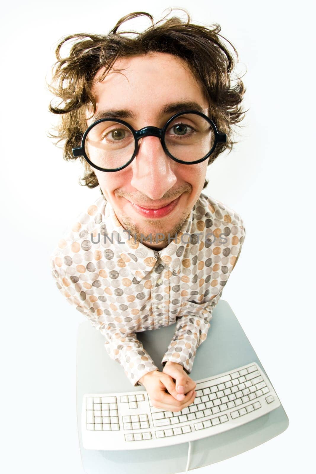 View from above of man in glasses sitting at desk with keyboard on it