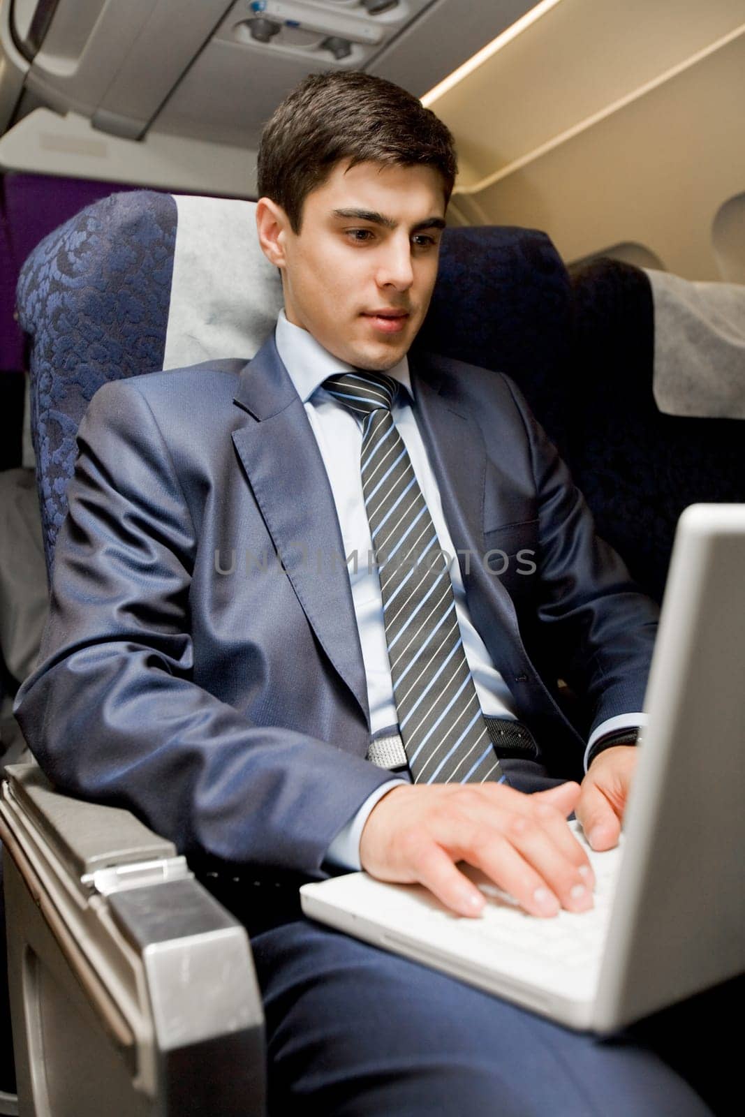 Image of busy male typing on laptop during flight