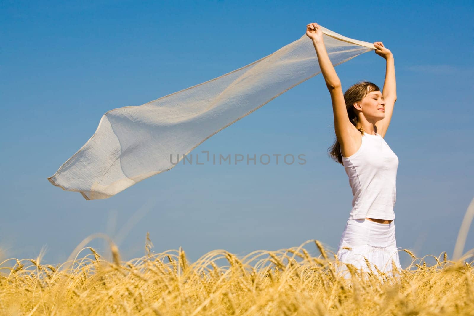 Portrait of pretty woman wearing white clothes and holding fluttering chiffon scarf in her hands