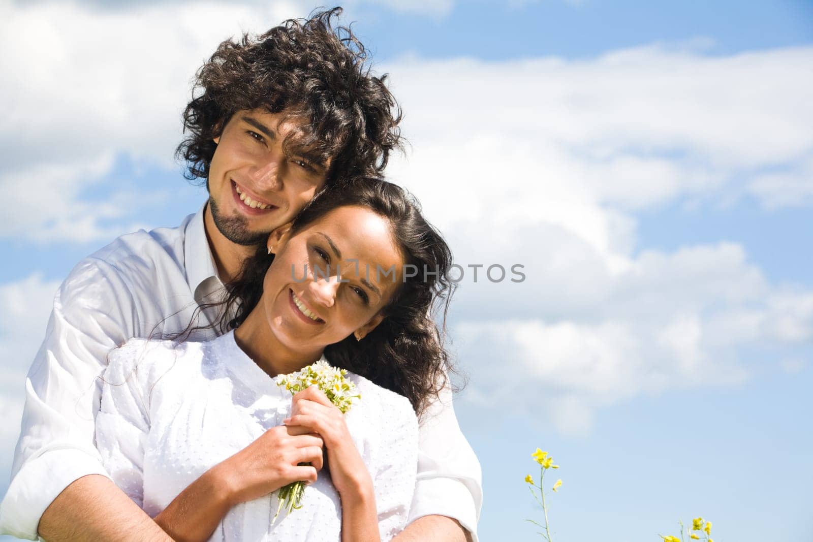 Portrait of smiling couple in white shirts on the background of sky