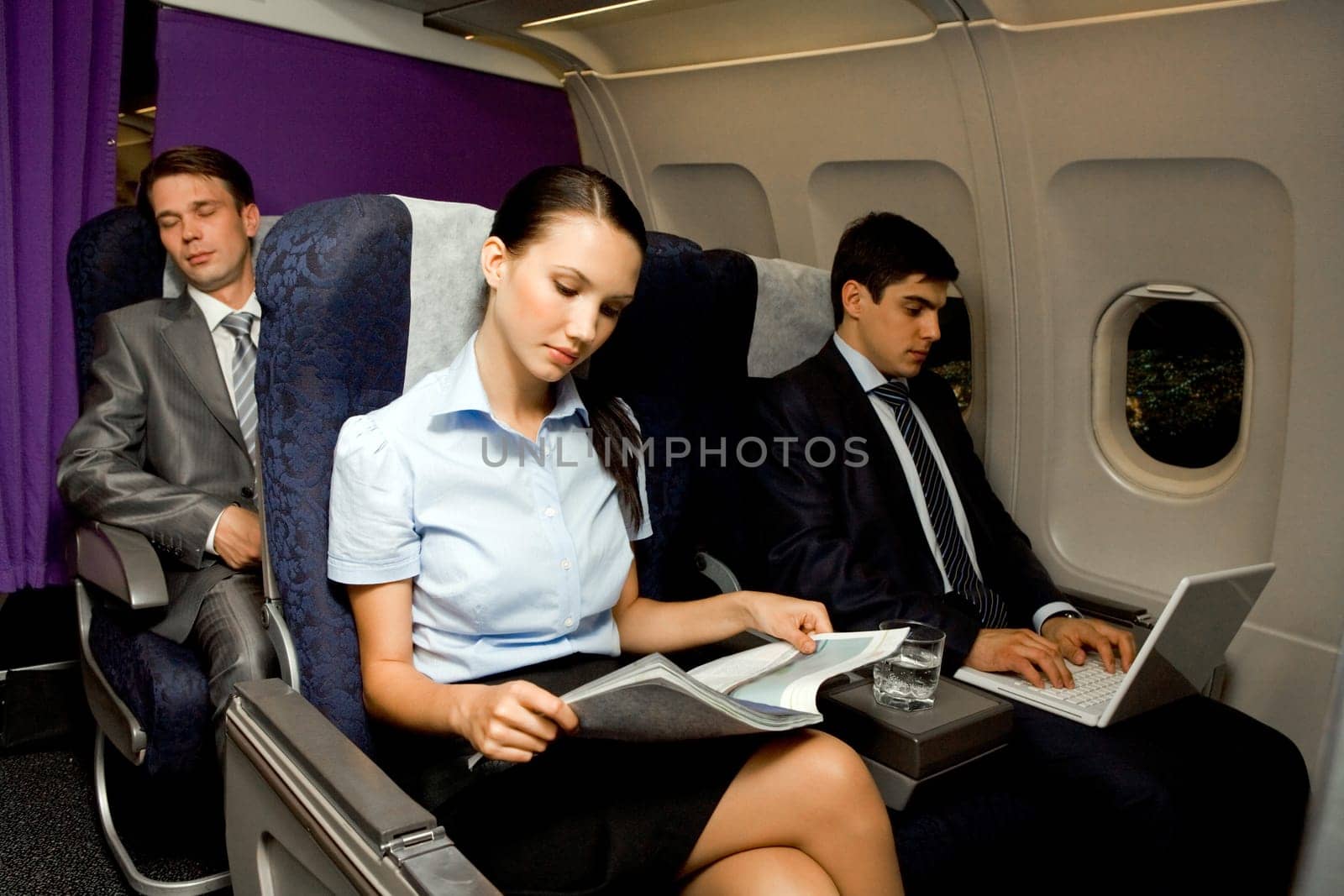Image of pretty girl reading magazine while handsome man typing next to her