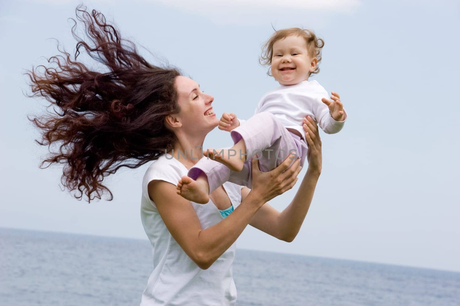 Joyful female playing with adorable infant on fresh air at summer