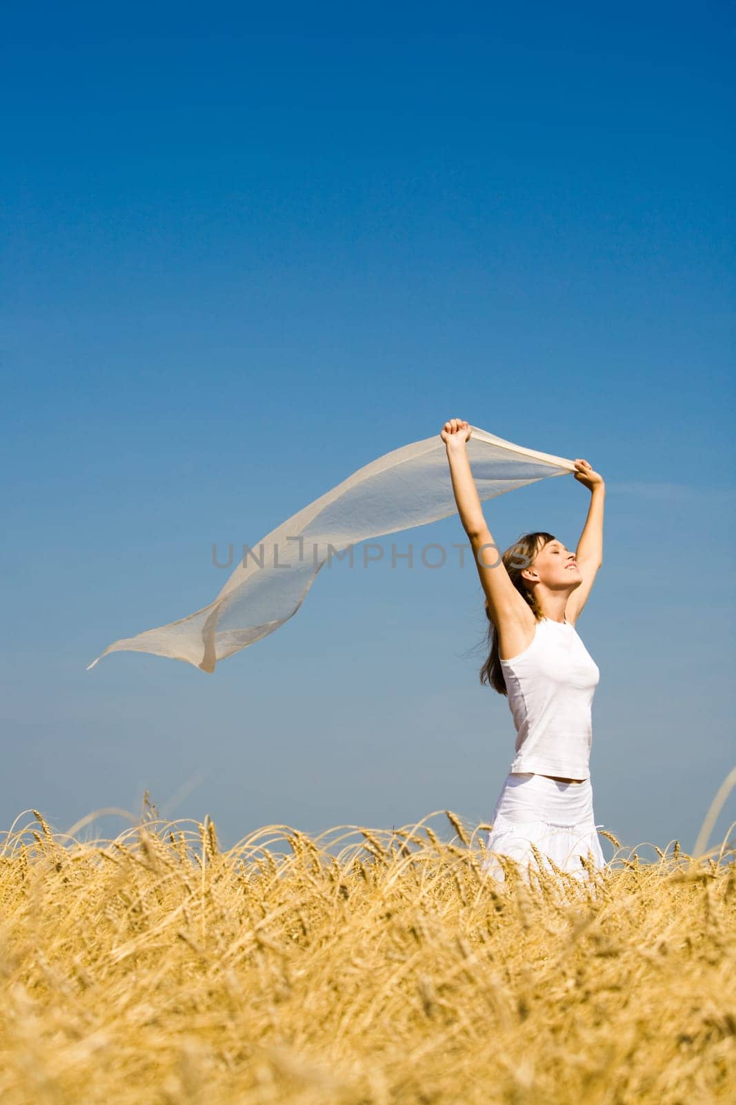 Portrait of pretty teenager holding fabric and standing in wheat field