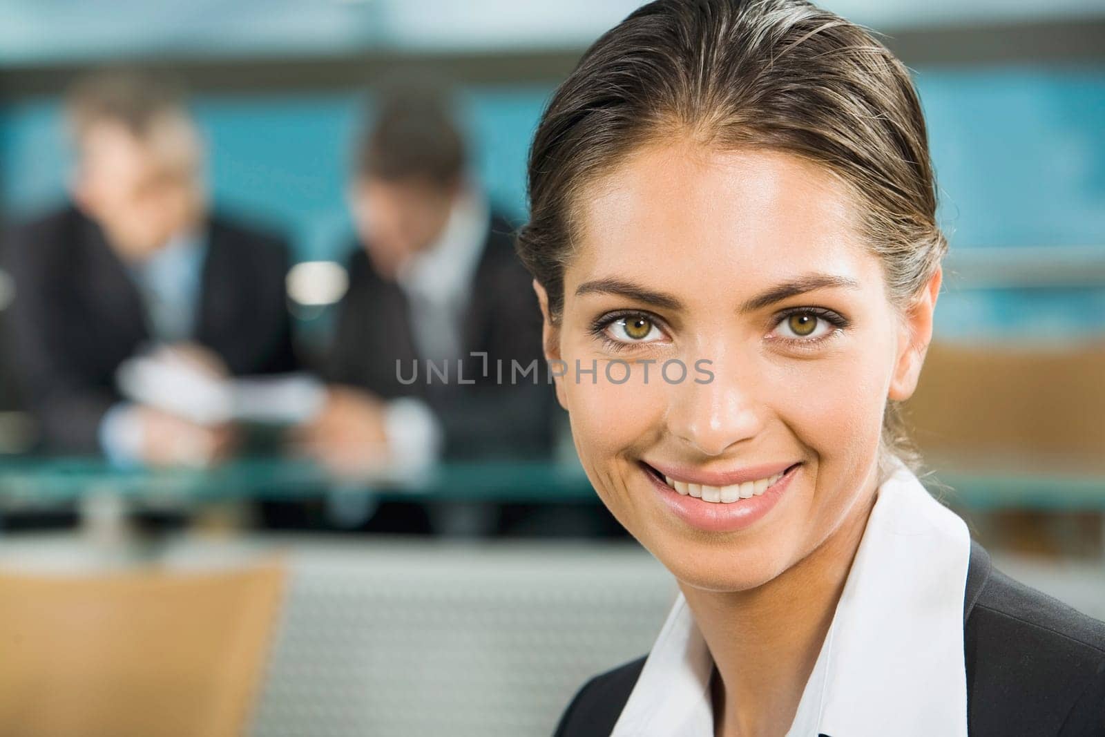 Close-up of beautiful woman smiling on the background of two businesspeople in a room