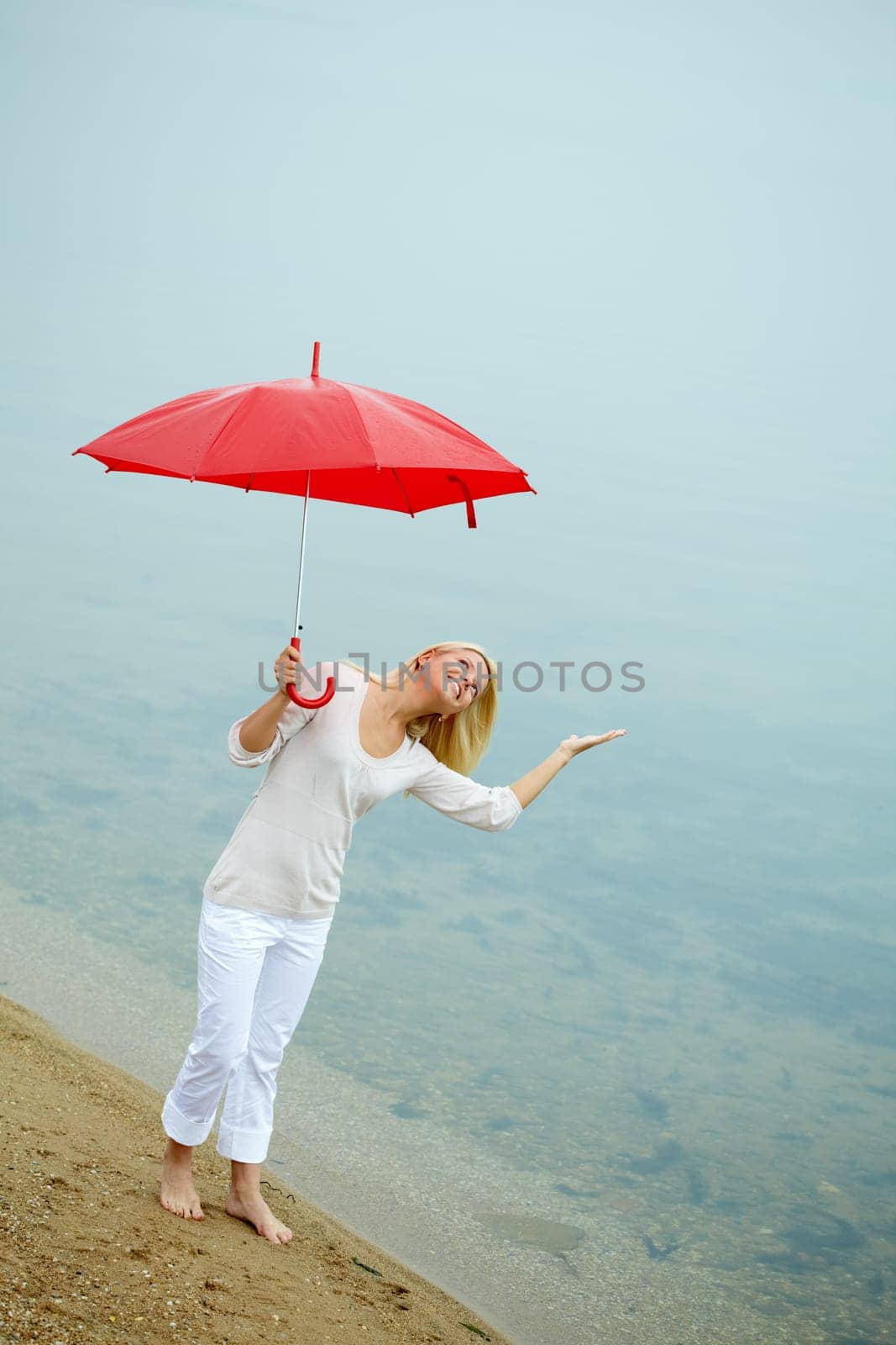 Portrait of happy young girl on the shore with umbrella