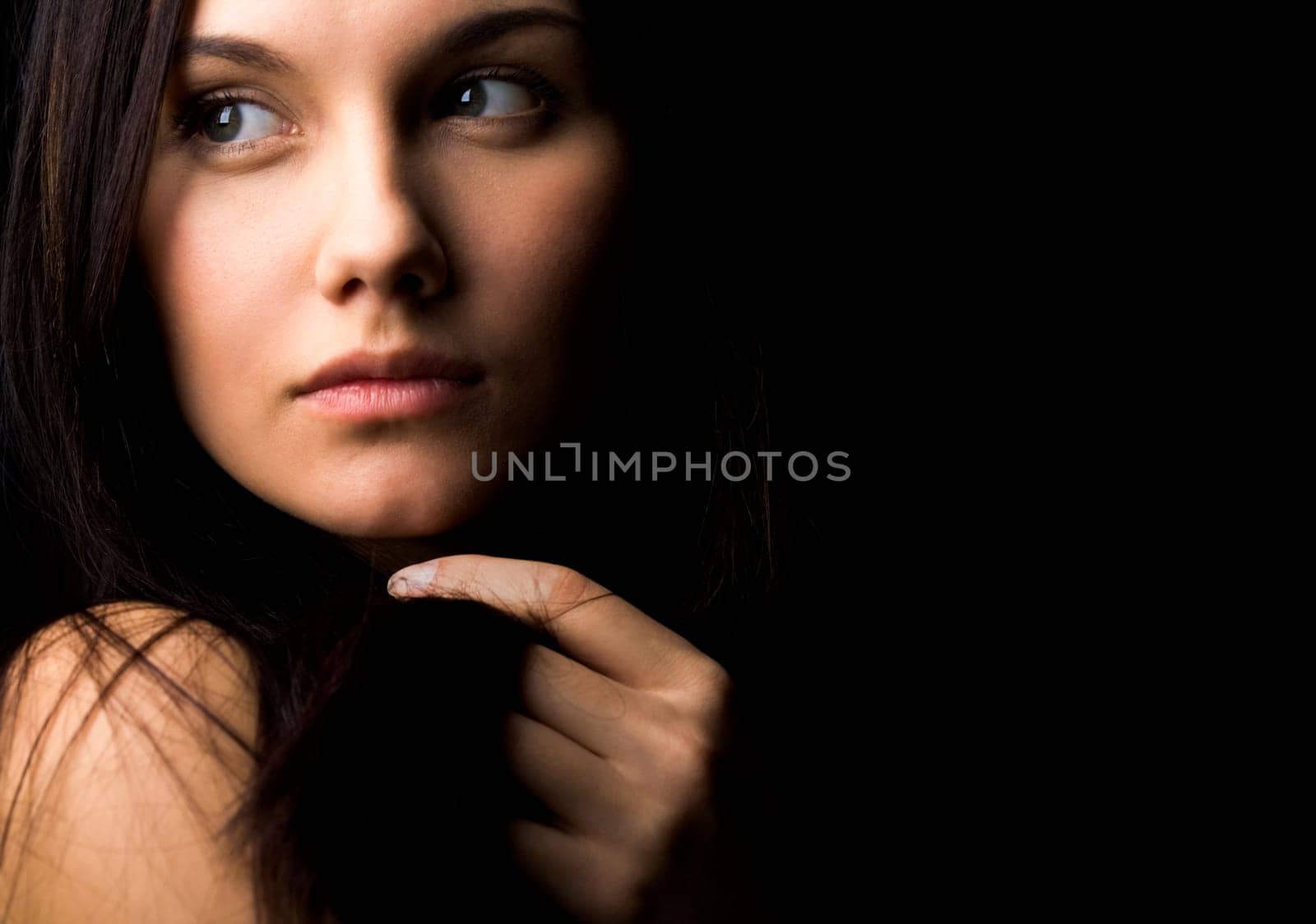 Image of gorgeous lady with dark hair touching it by hand and looking aside