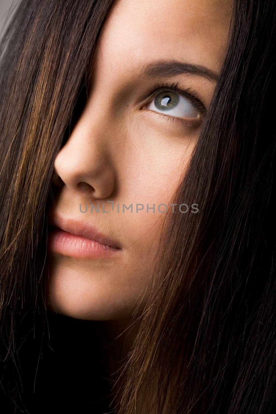 Part of face of young female with dark hair looking upwards