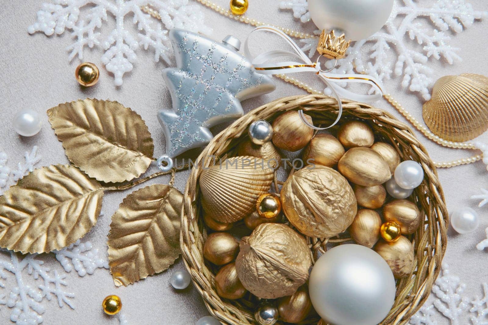 Golden nuts, shell, beads and white ball lying in the basket on the christmas backdrop