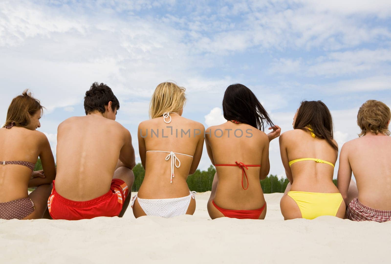 Portrait of backs of people sitting on the sand in row